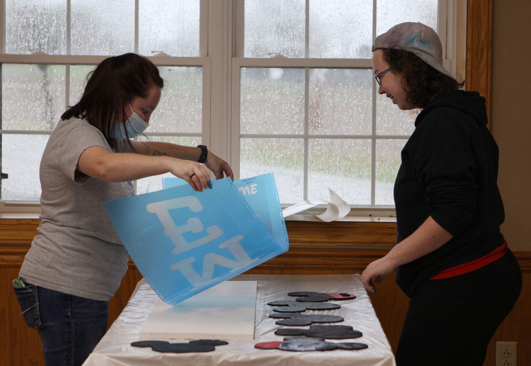 Kari Unerstall helps Nicole Frankenberg lay down a stencil